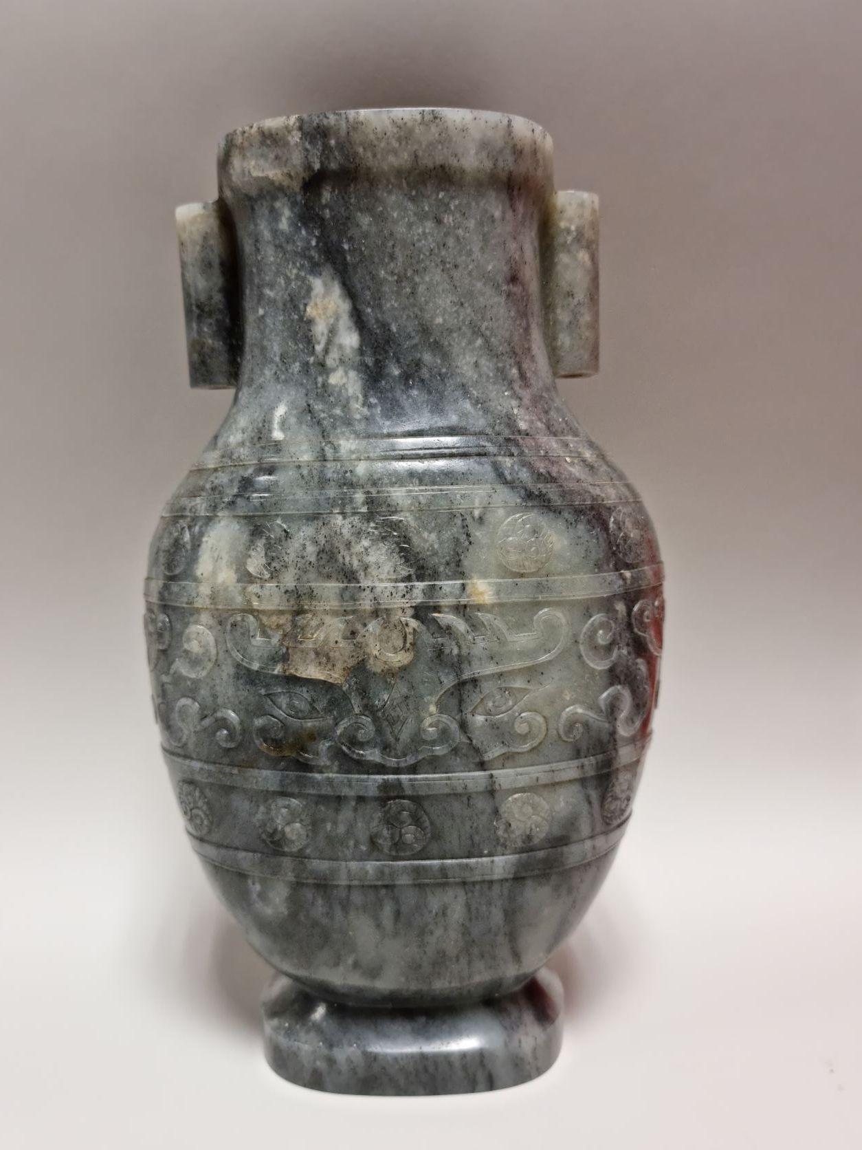 Null 中国，嘉庆时期（1796-1820）。灰色的青瓷玉胡瓶，半浮雕的饕餮面具装饰，在两个同心带之间有螺旋形马卡龙装饰的如意造型的云彩。它有两个管状的把手，&hellip;