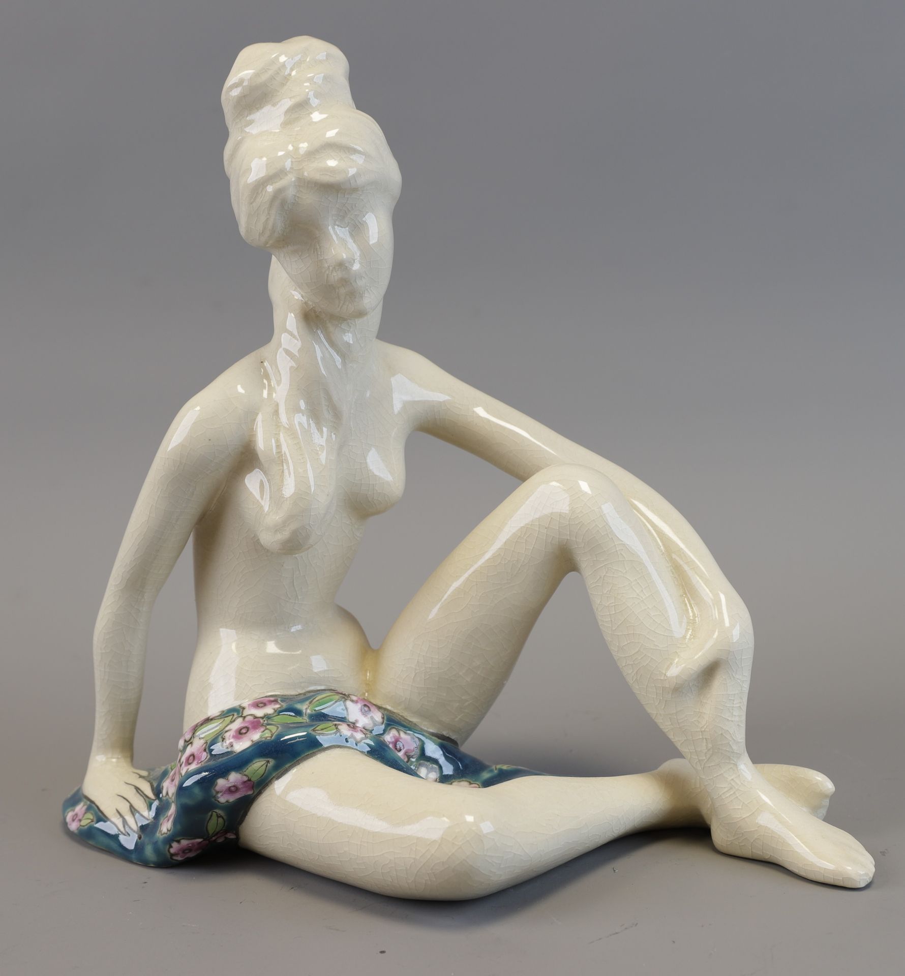 Null 一件精致的陶器和多色珐琅雕像，表现了一位年轻女性的坐姿，具有装饰艺术风格。 长：24.5厘米