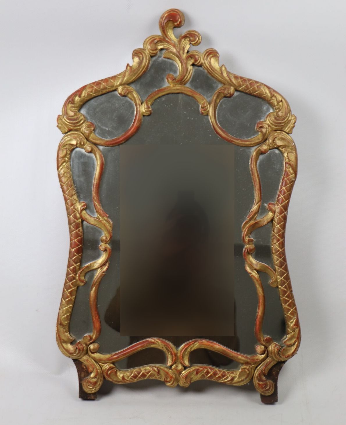 Null Miroir à pare-closes en bois sculpté et doré à décor d'enroulements.. 
Le c&hellip;