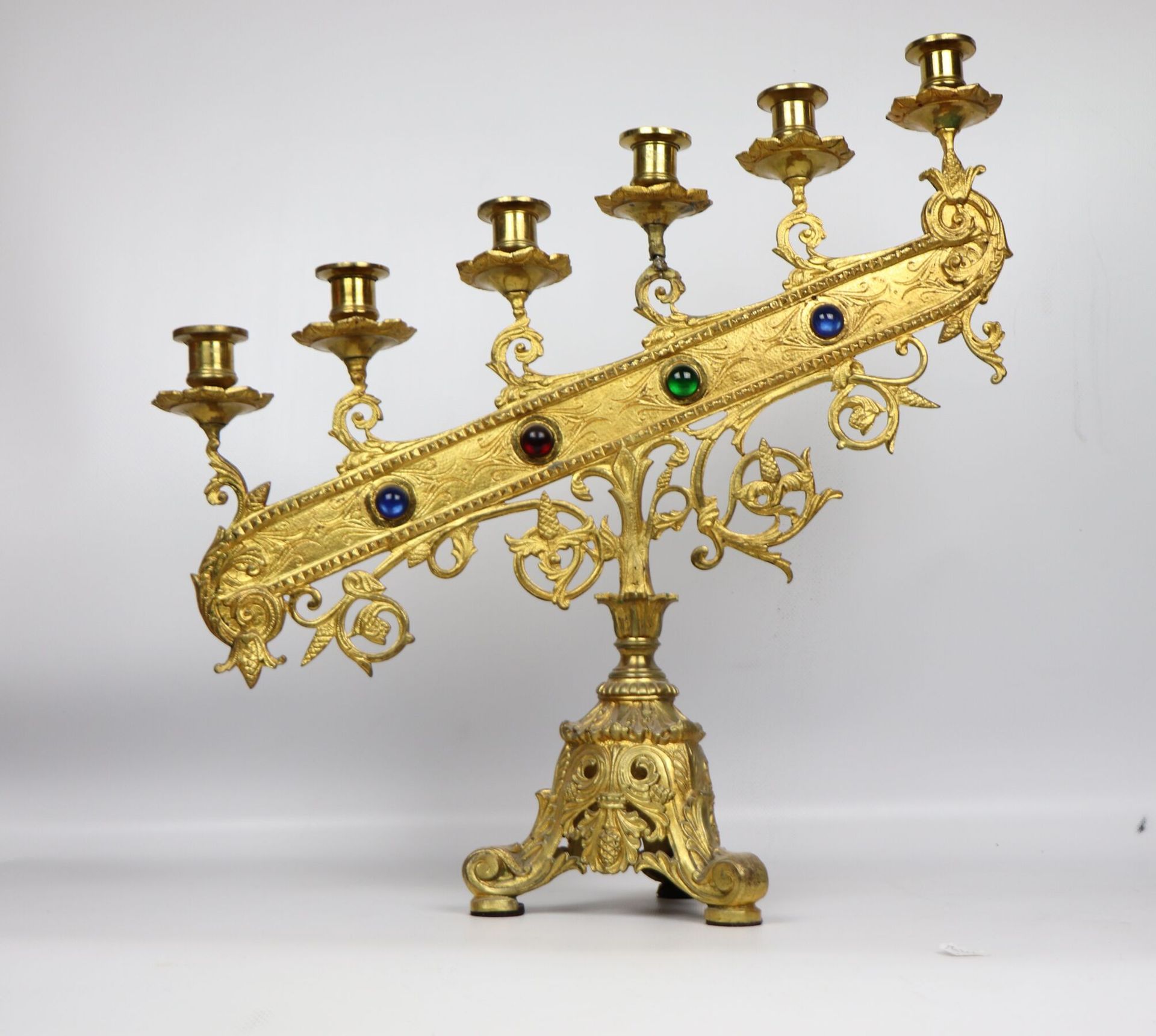 Null 鎏金青铜祭坛烛台有六个灯。 
上升的灯臂上装饰有四个彩色凸圆形宝石。
三角形的底座上有叶子的装饰。 
大约1900年。 
高_49厘米，宽_46厘米，&hellip;