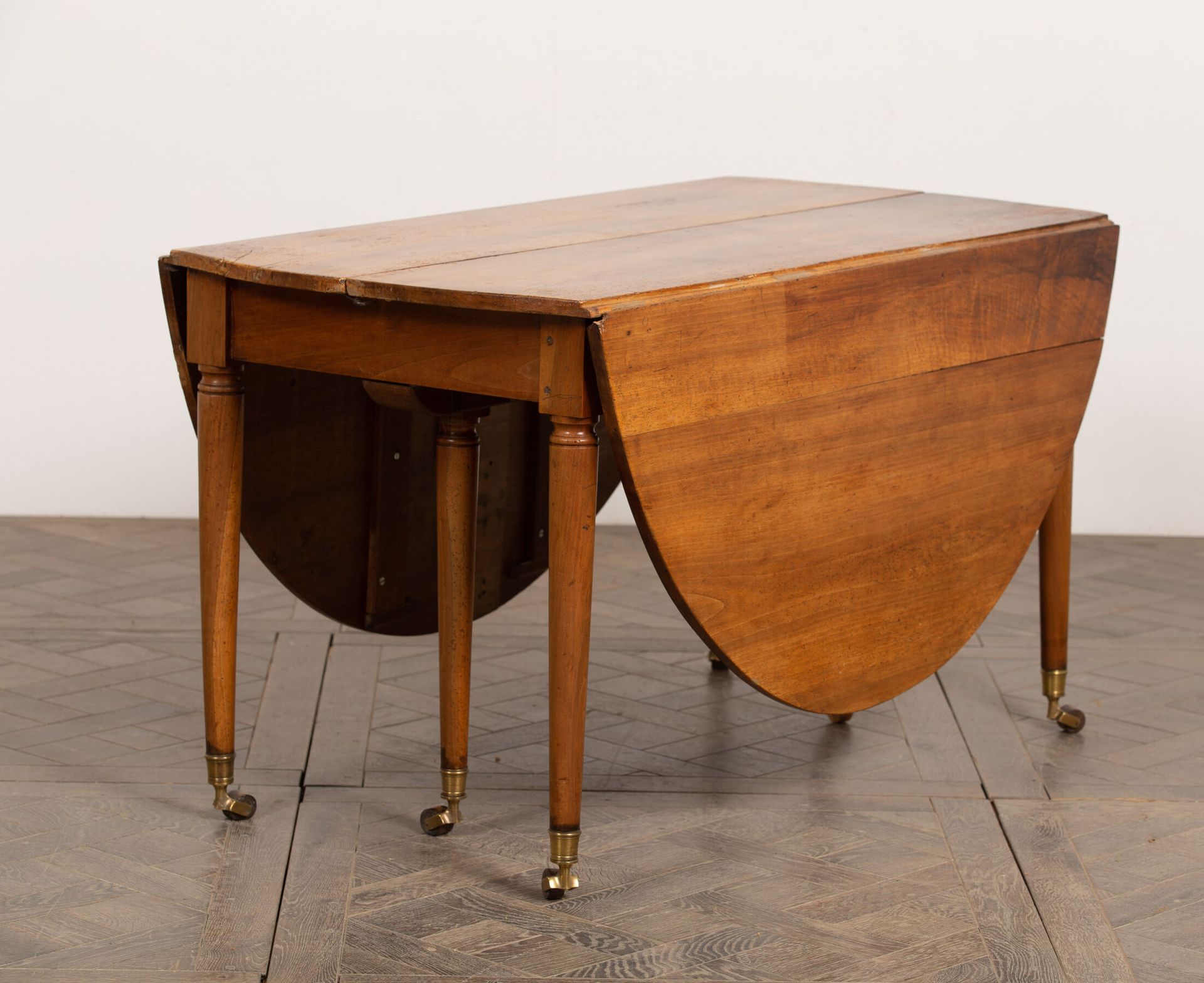 Null 胡桃木餐桌有两个圆形的侧板。 
它站在六个带脚轮的柱脚上。 
19世纪。
高_73.5厘米，宽_177.5厘米，长_129.5厘米，折叠后的宽度_33&hellip;