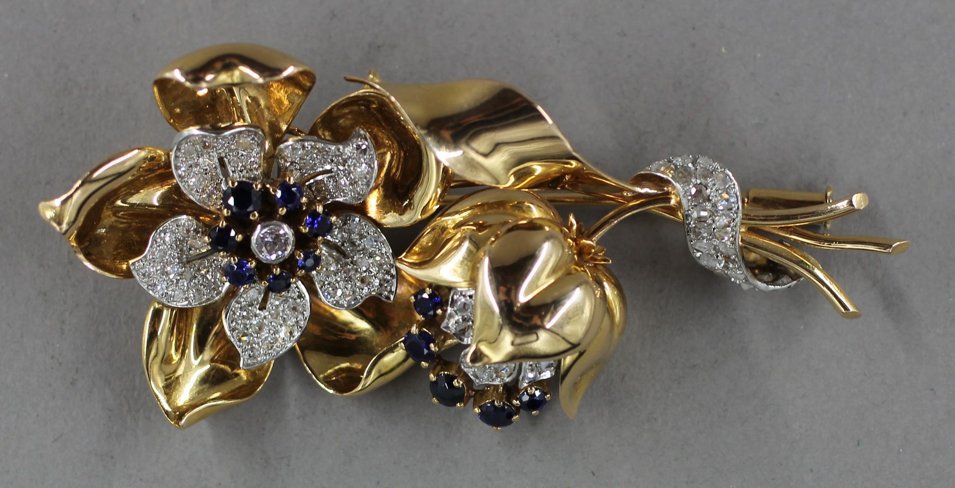 Null 18k黄金和铂金材质的胸针，镶有闪亮宝石和蓝宝石的花形，原重：26.3克。