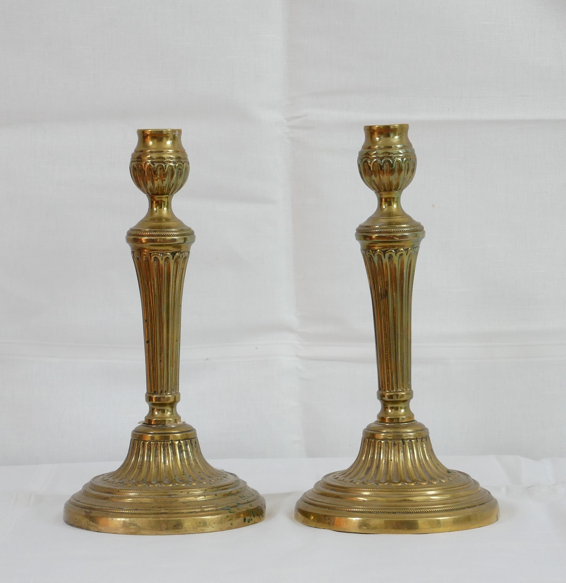 Null Paar Kerzenhalter aus godronierter Bronze im Stil Louis XVI.

H: 27 cm.