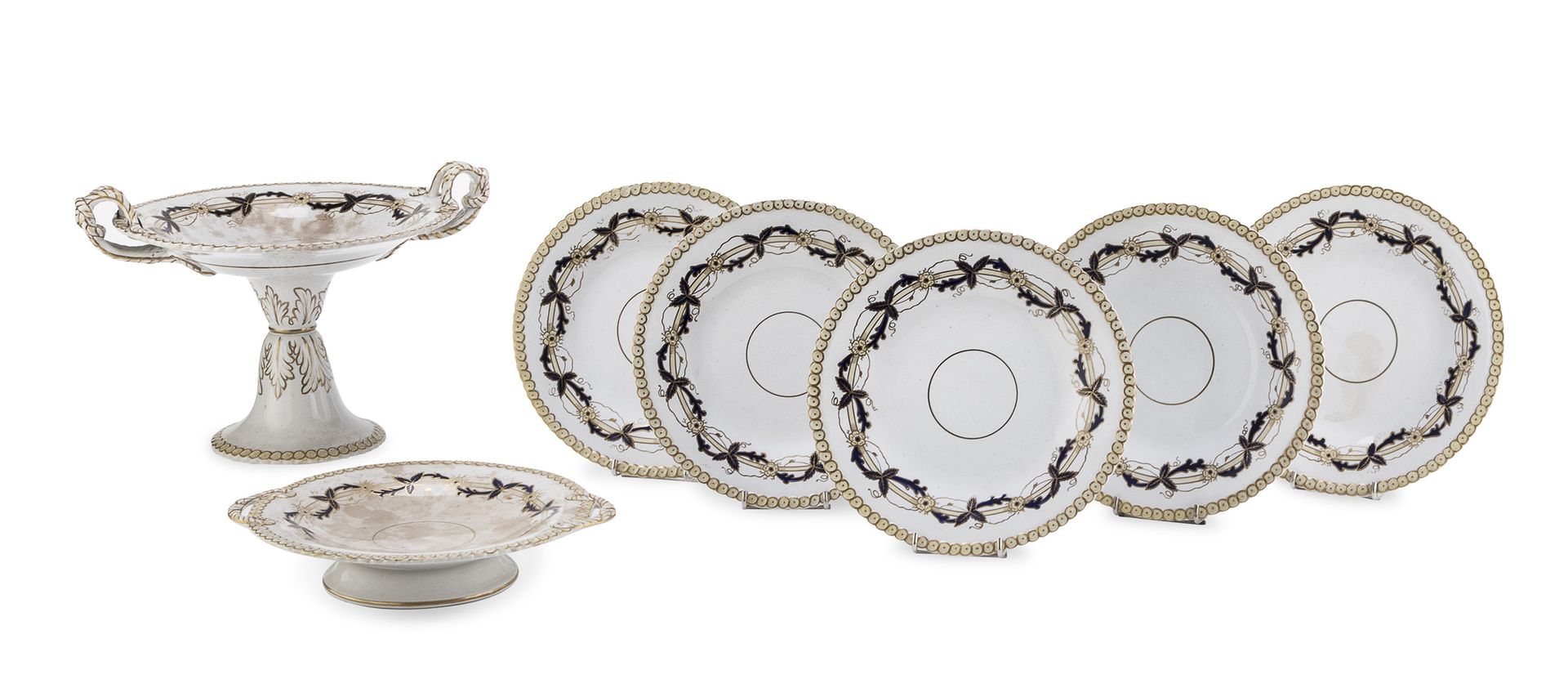 Null 陶器餐具的一部分，英国 19世纪末

有丝带和花环装饰，有鱼鳞状边框。由果盘、立柱和九个盘子组成。

粘贴中的雕刻标记。

测量水果碗，cm. 24 &hellip;