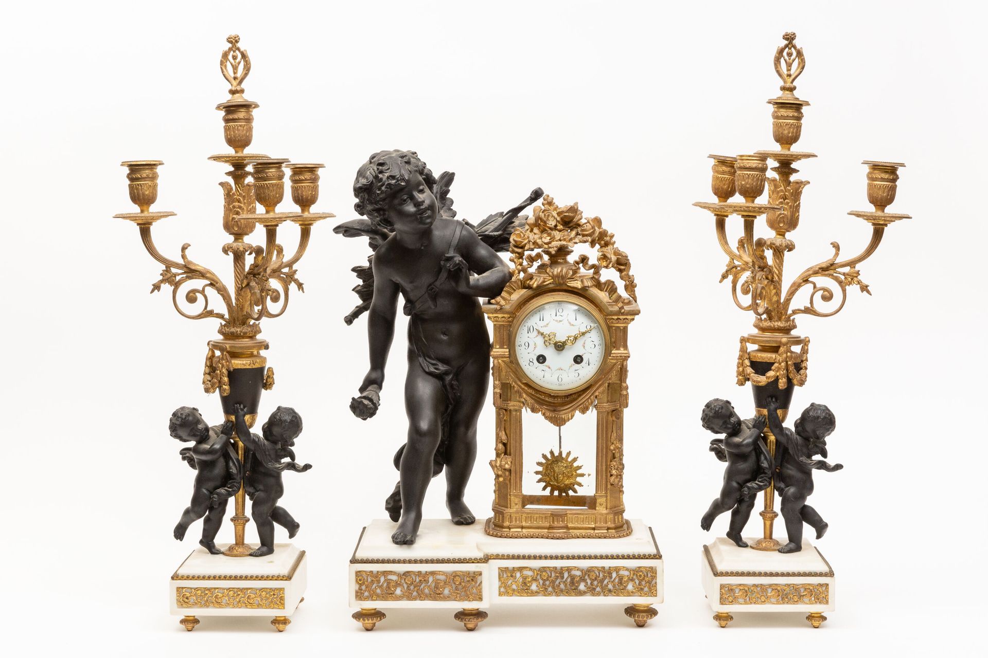 Null 
一套青铜色、鎏金青铜和白色大理石的壁炉，包括一个时钟和一个手持火炬的爱情人物，以及一对烛台，两个爱情人物手持一个有四盏灯的花瓶。




青铜器上装&hellip;