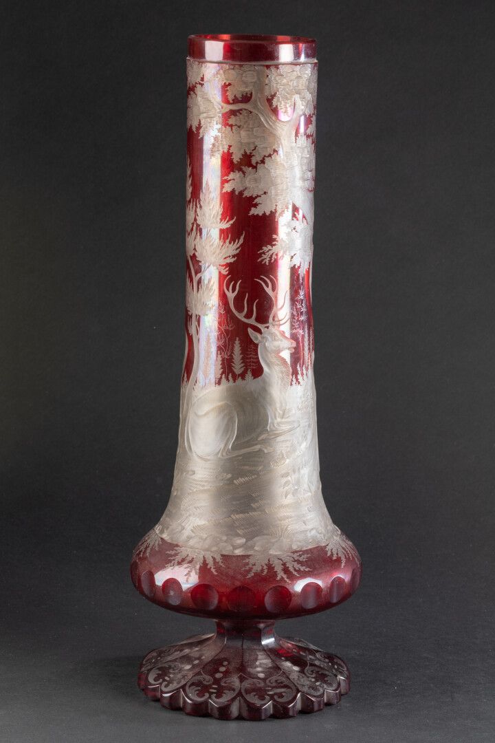 BOHEME - XIXe siècle 大管状花瓶，置于一个多棱形基座上，瓶身刻有两只雄鹿的狩猎装饰

双层水晶，无色和红宝石色

H.42厘米。