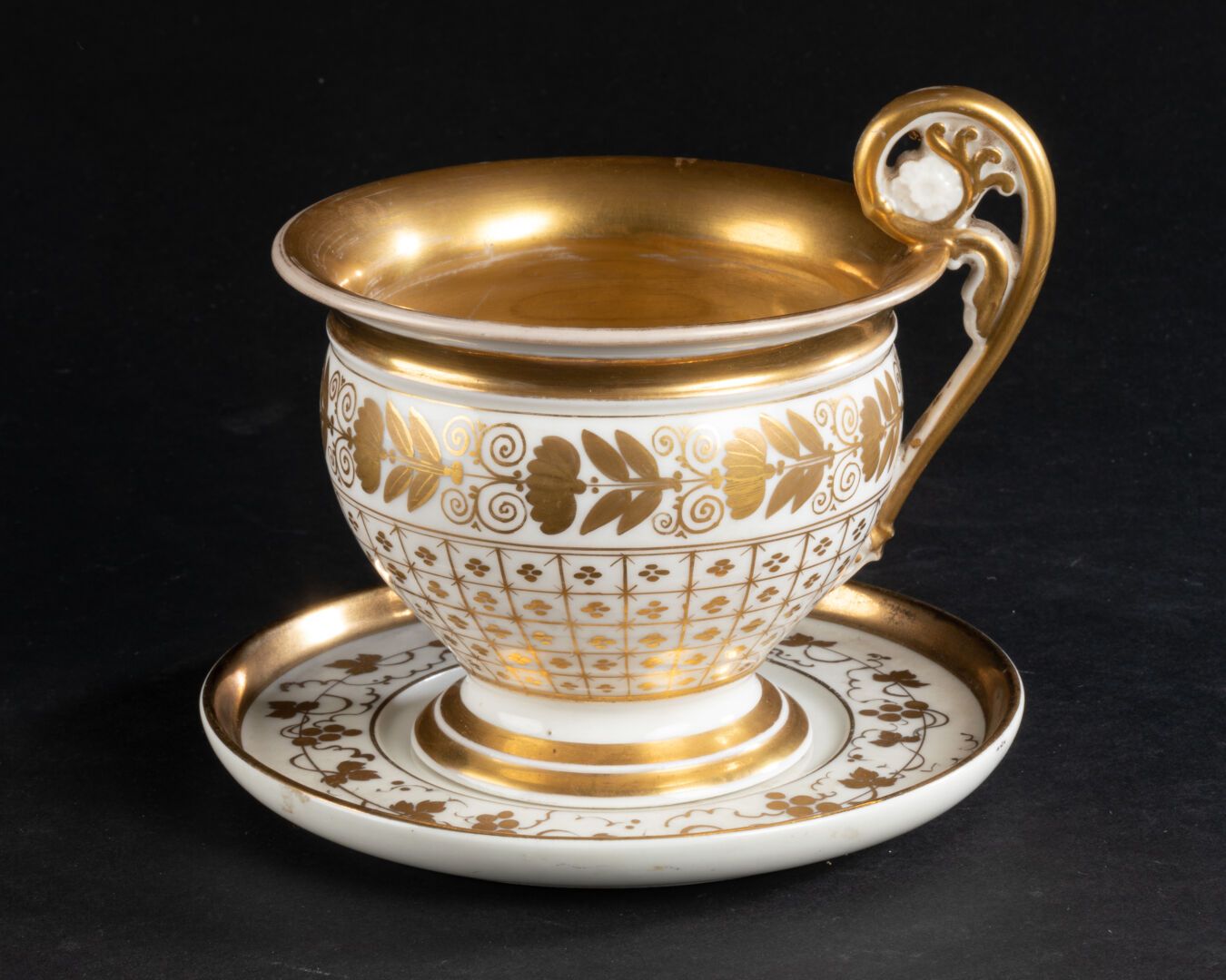 PARIS - XIXè SIÈCLE 杯子和它的茶盘

饰有花架、叶子和花环，手柄为卷轴式。

镀金图案的瓷器

高脚杯11厘米

D. 碟子14厘米