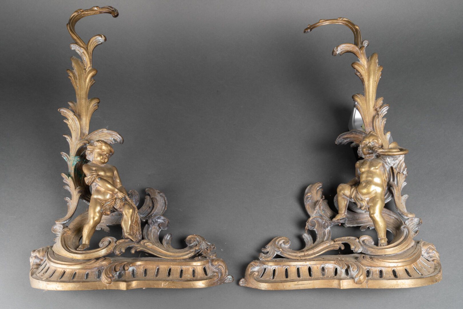 Null 一对带罗盖尔装饰和普蒂的CHENETS，一个拉着网，另一个吹着小号

凹凸不平的青铜

19世纪末的作品

H.55厘米。长：40厘米

氧化作用