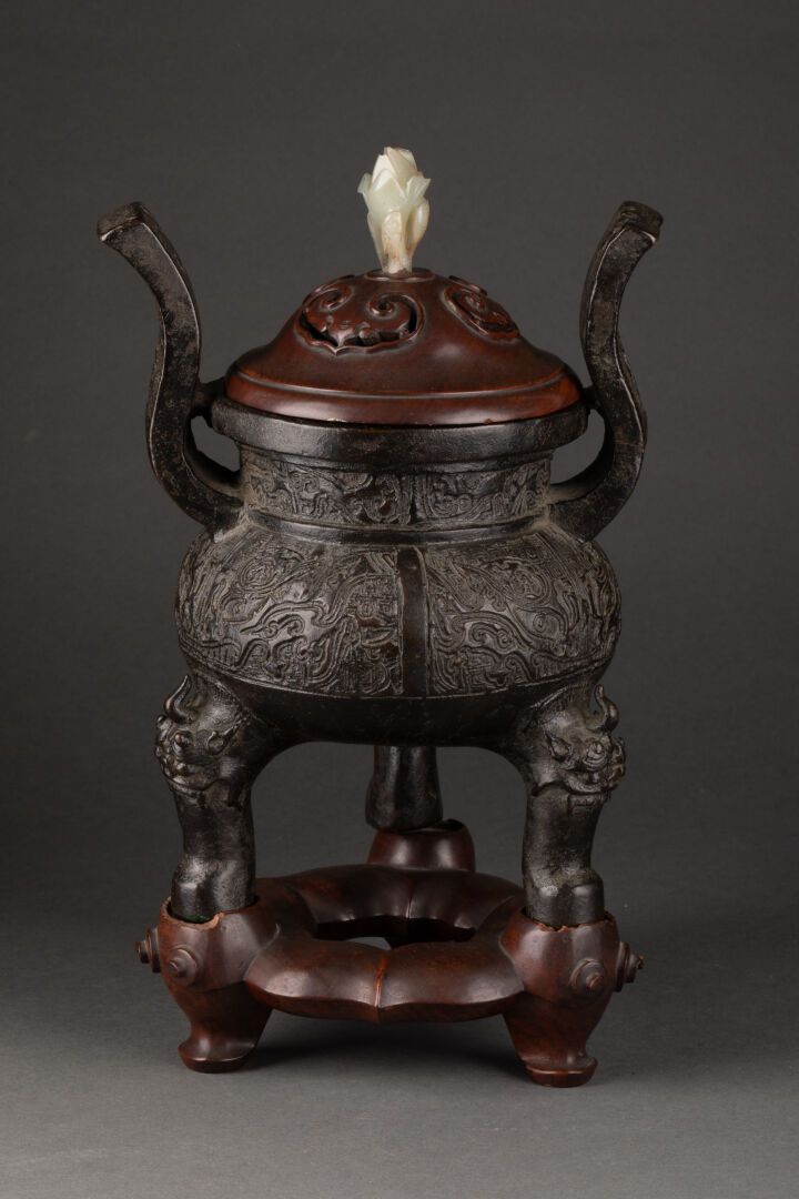 CHINE - Dynastie MING (1368-1644) 带有古代饕餮面具装饰的烧烛台

三角形底座上装饰有Fô狗头。

发光的青铜，模制和雕刻的木制&hellip;