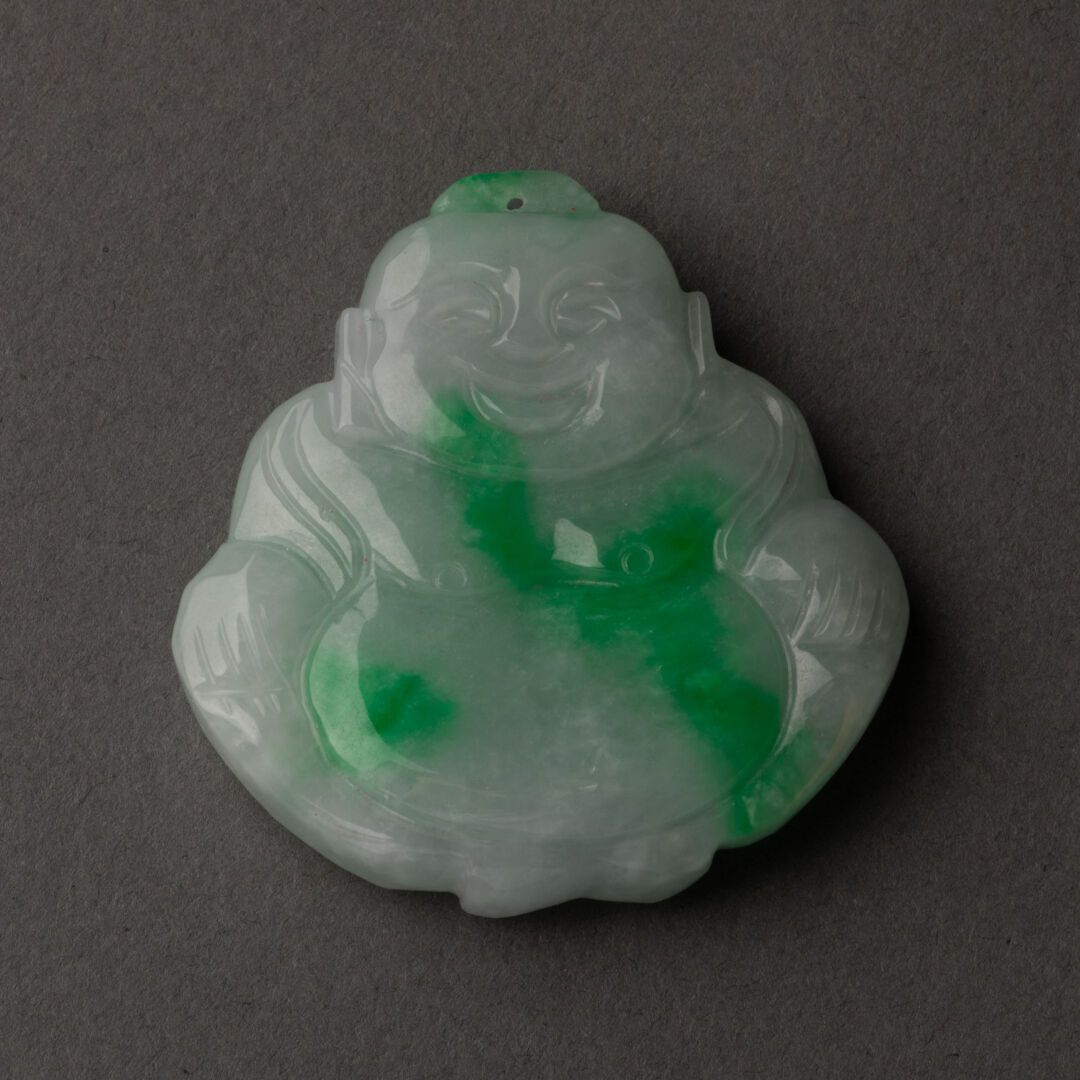 CHINE - XXe siècle Budai Pendant 

Carved and incised jadeite 

H. 5 cm - L. 4,5&hellip;