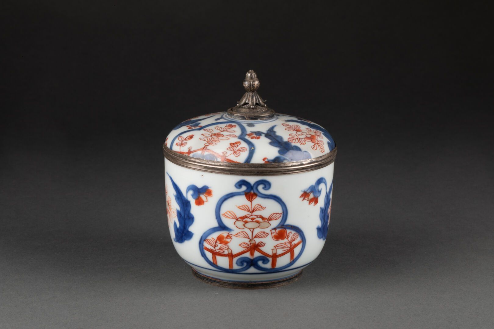 CHINE - XVIIIe siècle 伊万里风格的带花装饰的有盖烛台

瓷器和多色珐琅，银框

H.11 cm - D. 9.3 cm

修复后的盖子