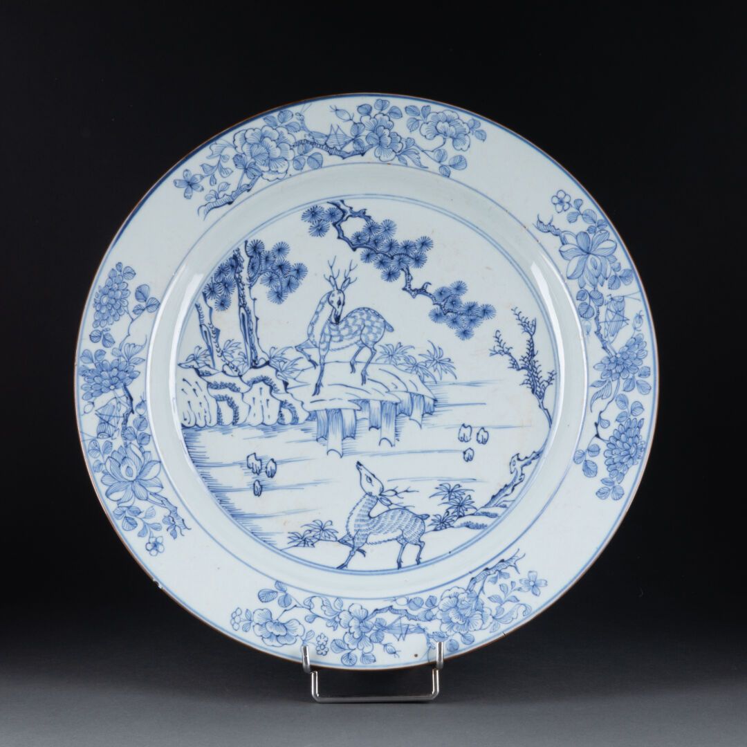 CHINE - XVIIIe siècle 空心圆盘，装饰有风景中的小鹿 
瓷器和蓝色釉下彩 
D. 38.5厘米 
机翼上的裂缝和碎片