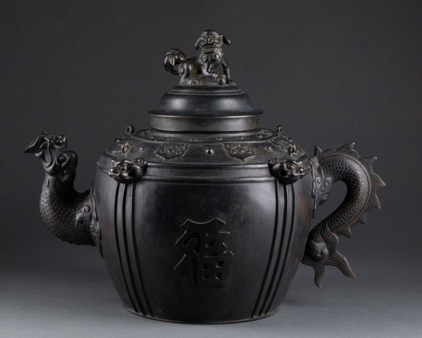 CHINE - XIXe siècle 大茶壶，装饰有象形文字、如意和佛狗。 
龙形的手柄 
带有黑色铜锈的青铜器 
H.27 cm - L. 37 cm