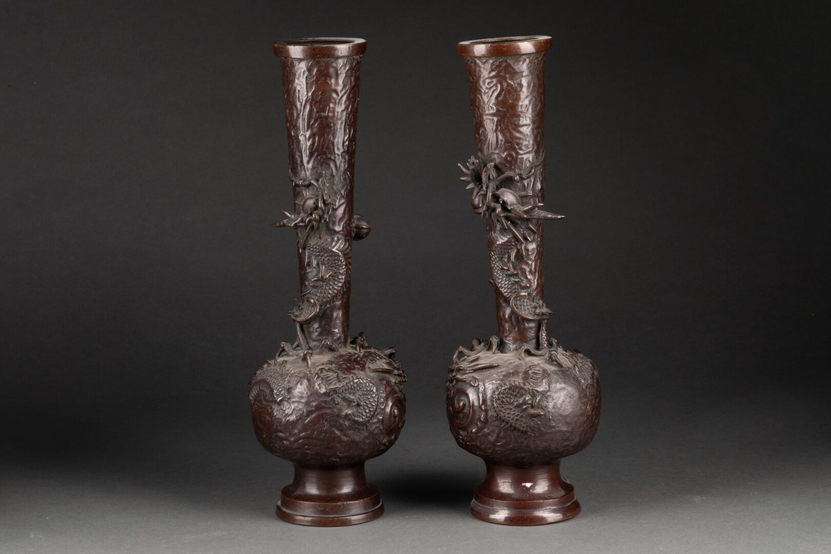 CHINE Début XXe siècle 一对球体和截顶锥体颈部的花瓶 
浮雕中的龙的装饰 
带有棕色铜锈的青铜器 
H.30厘米