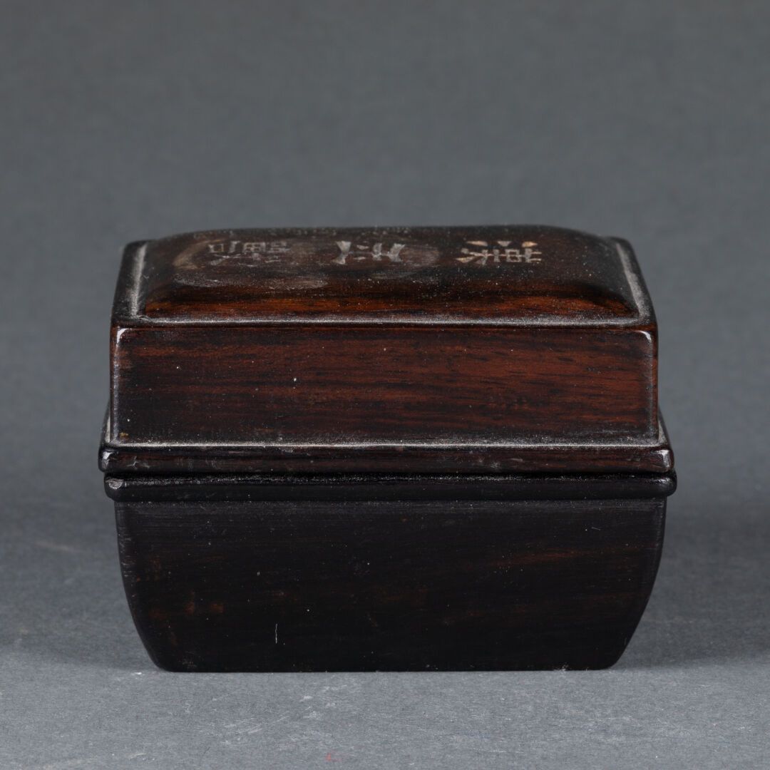 CHINE - XXe siècle 长方形截面的有盖小盒 
盖子上刻有表意文字 
雕刻和抛光的木材 
H.5 cm - L. 7 cm 
小颠簸
