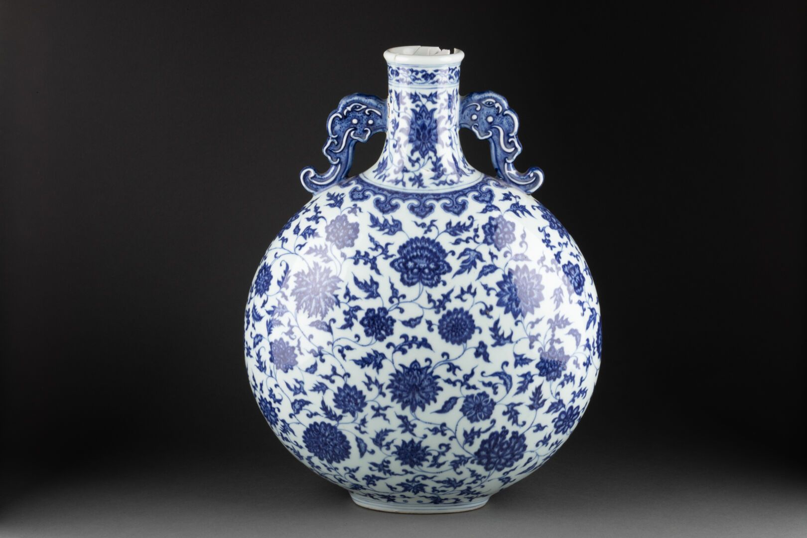 CHINE - XVIIIe ou XIXe siècle 扁壶（月光瓶）高脚杯，饰有荷花的叶子 
古老的龙形状的把手 
瓷器和蓝色釉下彩 
乾隆皇帝的蓝六字篆&hellip;