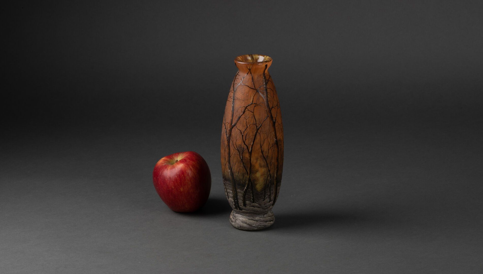 DAUM Nancy 基座上的纺锤形花瓶，颈部狭窄 
橙色背景上的冬季景观与树木的装饰 
酸蚀和搪瓷玻璃 
下面有洛林十字架的签名 
H.21厘米