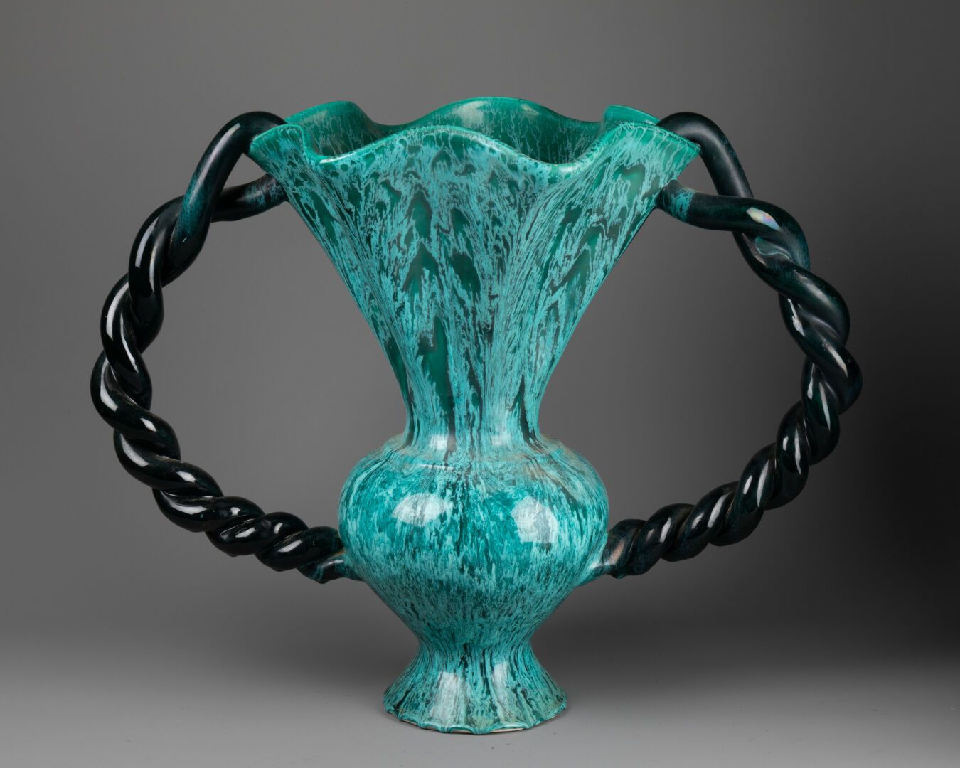 Marius GIUGE (1909-1980) pour VALLAURIS 大型花瓶，颈部呈喇叭状和多叶状 
两个扭曲的手柄 
绿松石釉面陶器 
底下有三张&hellip;