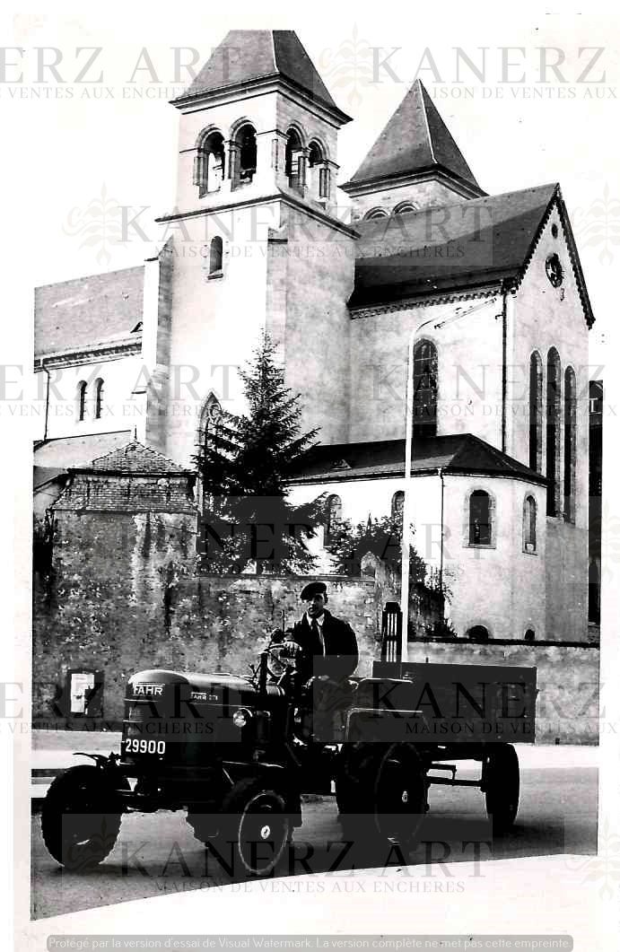 (AUTOMOBILE) Homme dans un tracteur devant une église, années 1956 57