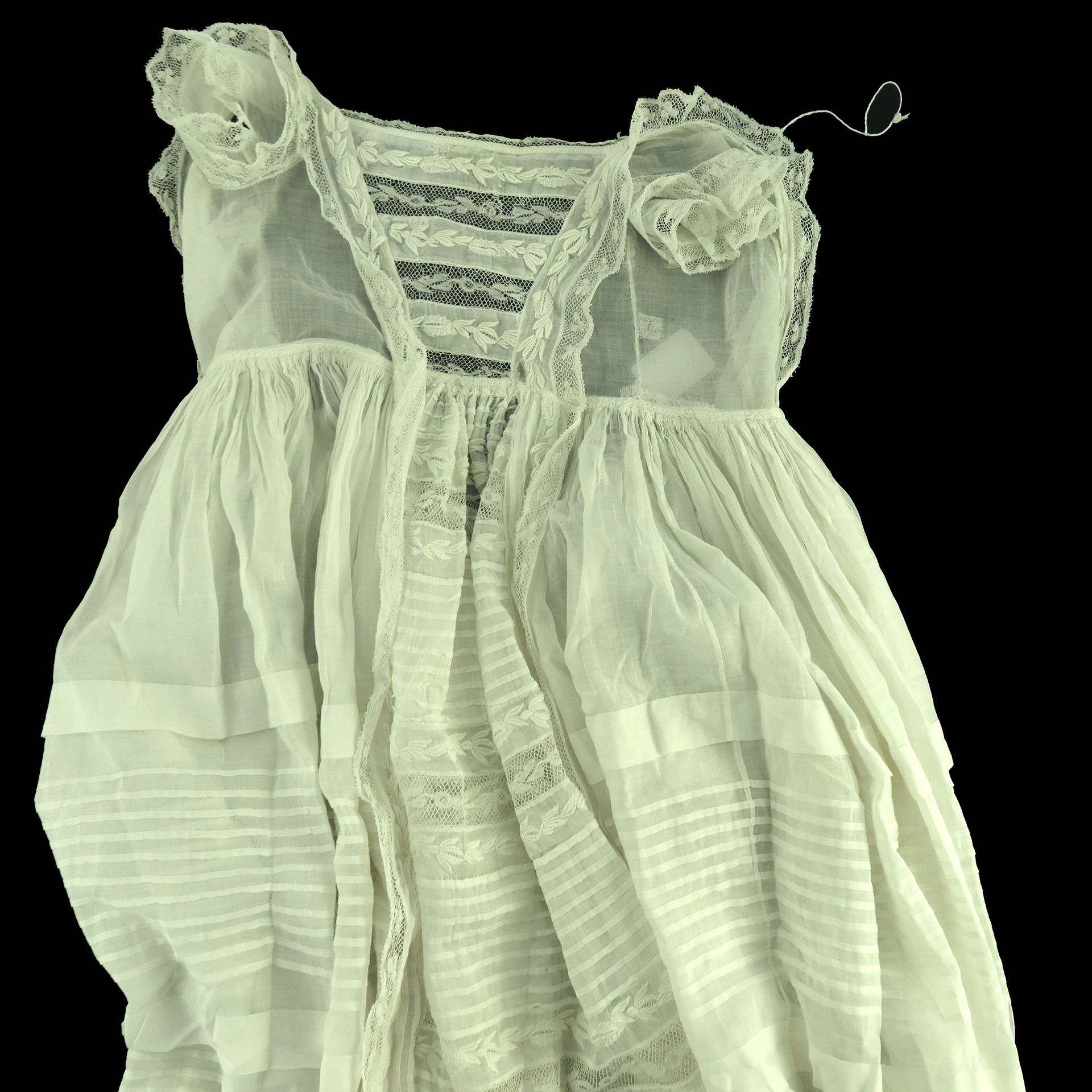 Null 两件19世纪的纯棉草坪洗礼袍，裙子都特别长，第一件有大量的褶裥，前面有蕾丝荷叶边，前面的褶裥与Valenciennes风格的蕾丝交替出现，短袖有三重荷&hellip;