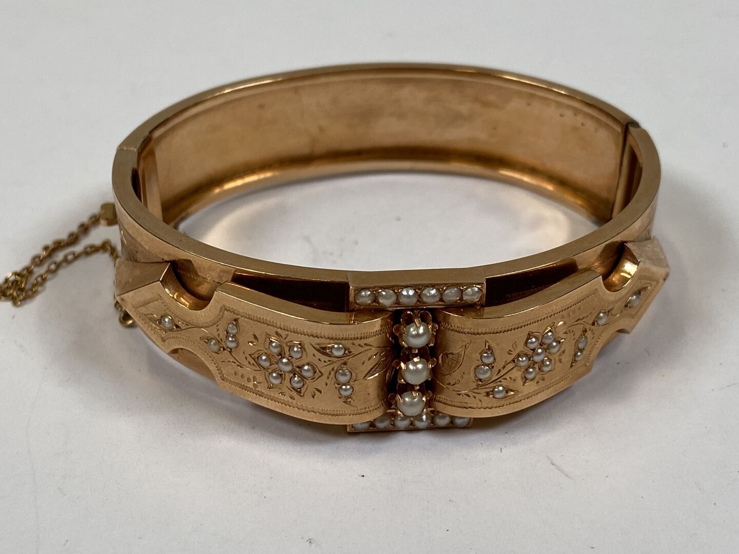 Null 大型18K黄金手镯，小珍珠镶嵌在封闭式和爪式镶嵌中，装饰有风格化的花朵和叶子的楣形图案。带安全链。

19世纪末，20世纪初。

毛重：19.6克。
&hellip;
