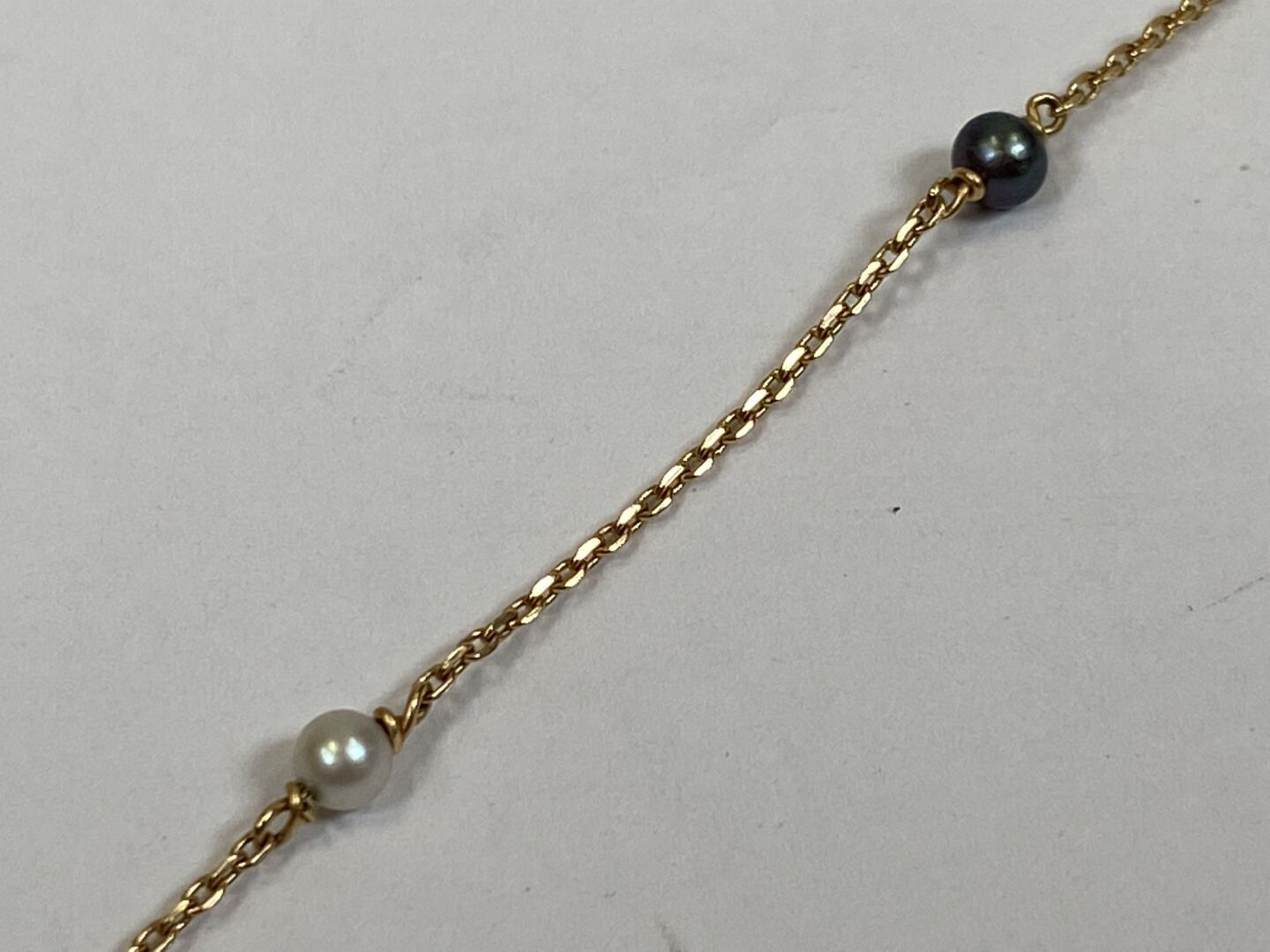 Null Bracelet in 18K yellow gold with 3 small grey and 2 white pearls.

Gross we&hellip;