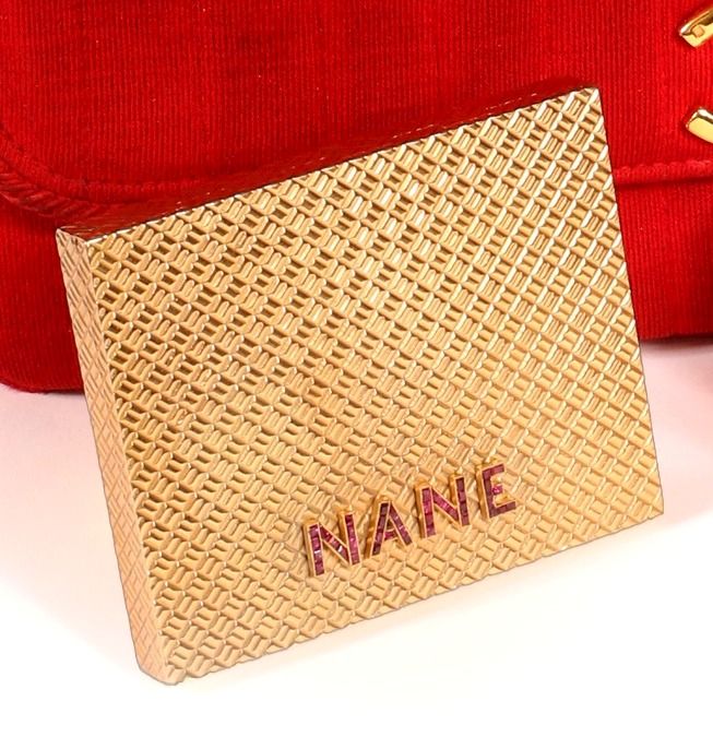 Null * 矩形粉盒，18K黄金750/000，有条纹图案，装饰有四个应用字母NANE，并镶嵌有校准的红宝石

1 x 6.5 x 8 厘米

毛重：145克