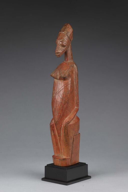 Null 罕见的娃娃，代表一个女人双手放在膝盖上坐着。
带红色铜锈的木材。
库伦巴人，上沃尔特。
H.28厘米。
出处：威廉-布里尔收藏。纽约。
书目：1974&hellip;