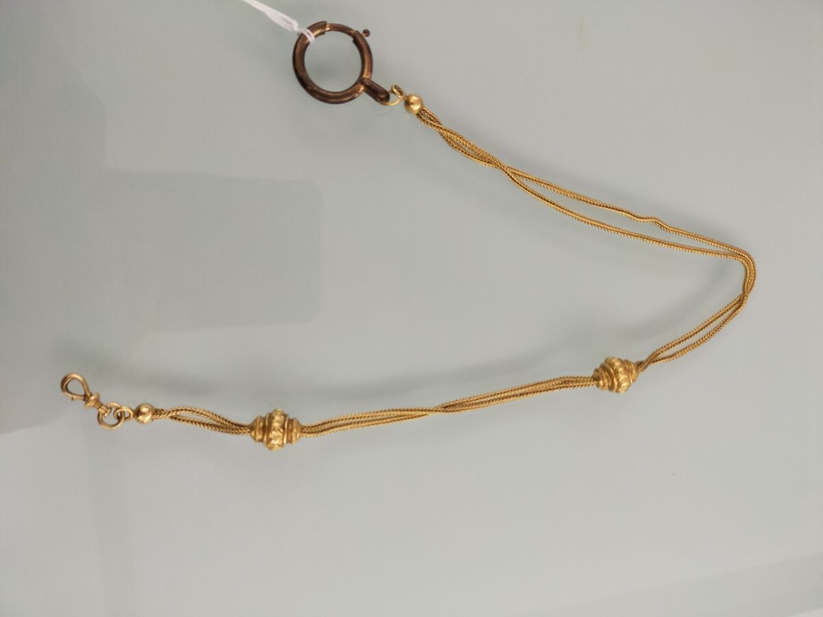 Null 黄金750千分之一的链式马甲，饰有两个流苏，并持有一个金属环。
1900年左右的法国作品。
(穿)。
长度：36厘米
毛重 : 19,3 g