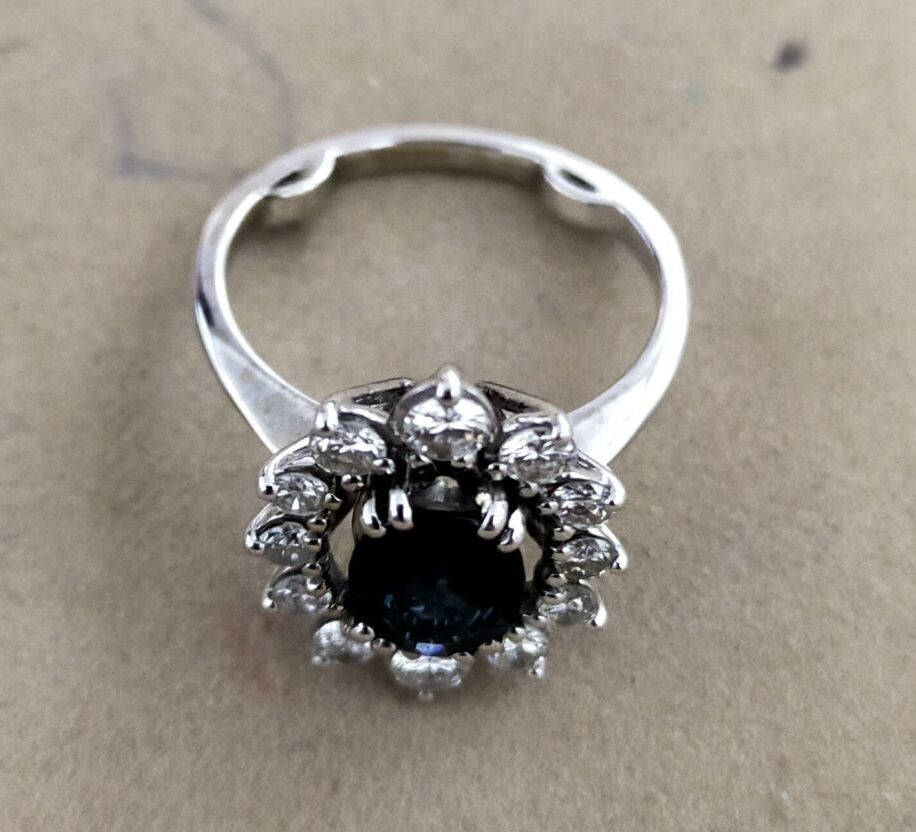 Null 白金戒指750千分之一，在一圈12颗圆形明亮式切割钻石中，以一颗椭圆形蓝宝石为中心装饰。
转指：49（球）
毛重：4,5克