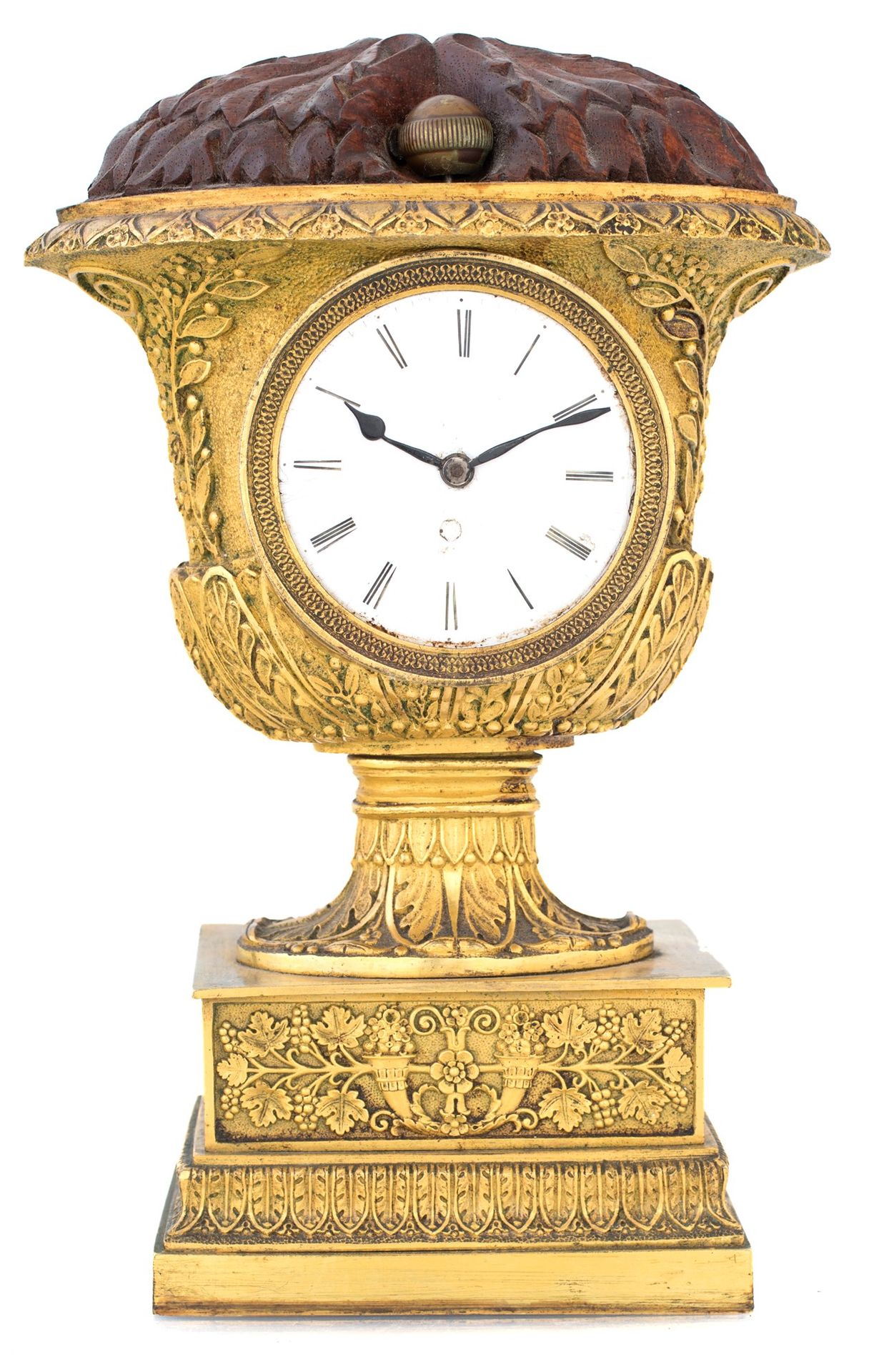 Table clock in bronze and wood 像一个精心凿制的杯子，上面有自然主义的图案，中心是一个带有罗马数字的白色珐琅表盘；顶部是雕刻的木材