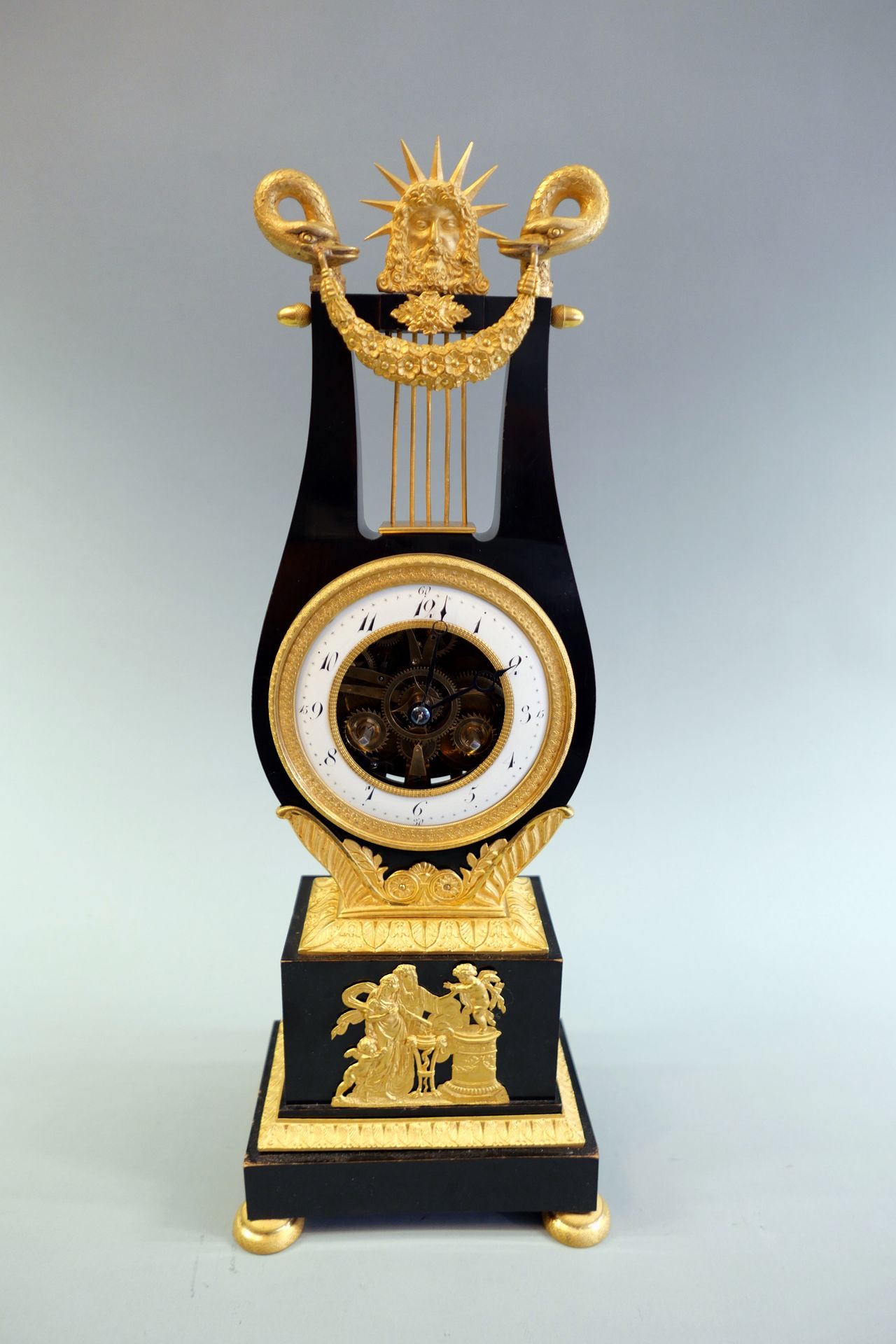 Empire Lyra-Uhr 黄铜材质，经过抛光处理。琴形的钟盒放在一个带有球脚和叶状浮雕的长方形底座上。冠以花环、天鹅和奥林匹亚神宙斯。装饰性穿孔表盘，白色&hellip;