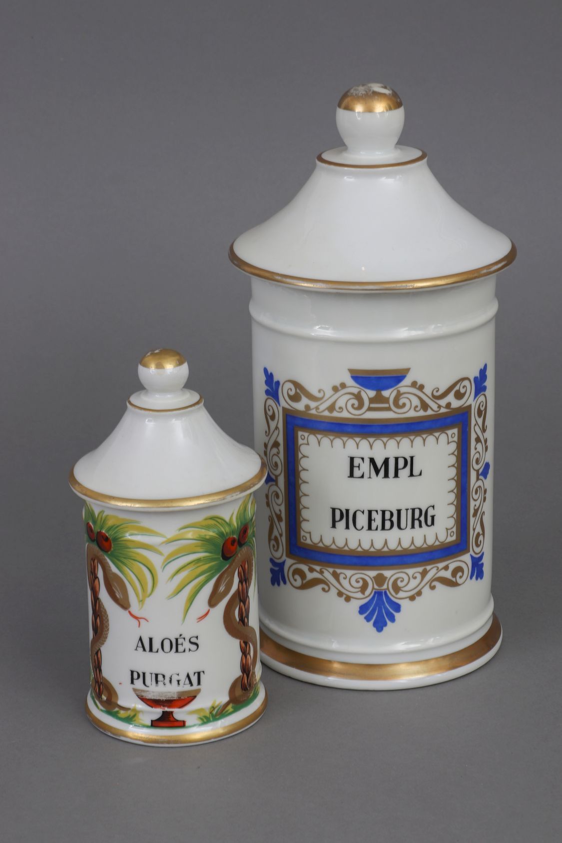 Null 2个19世纪风格的药剂师罐，法国，瓷器，圆柱形的罐体，带球形旋钮的尖盖，1个在正面刻有 "EMPL PICEBURG"，1个刻有 "ALOÉS PUR&hellip;