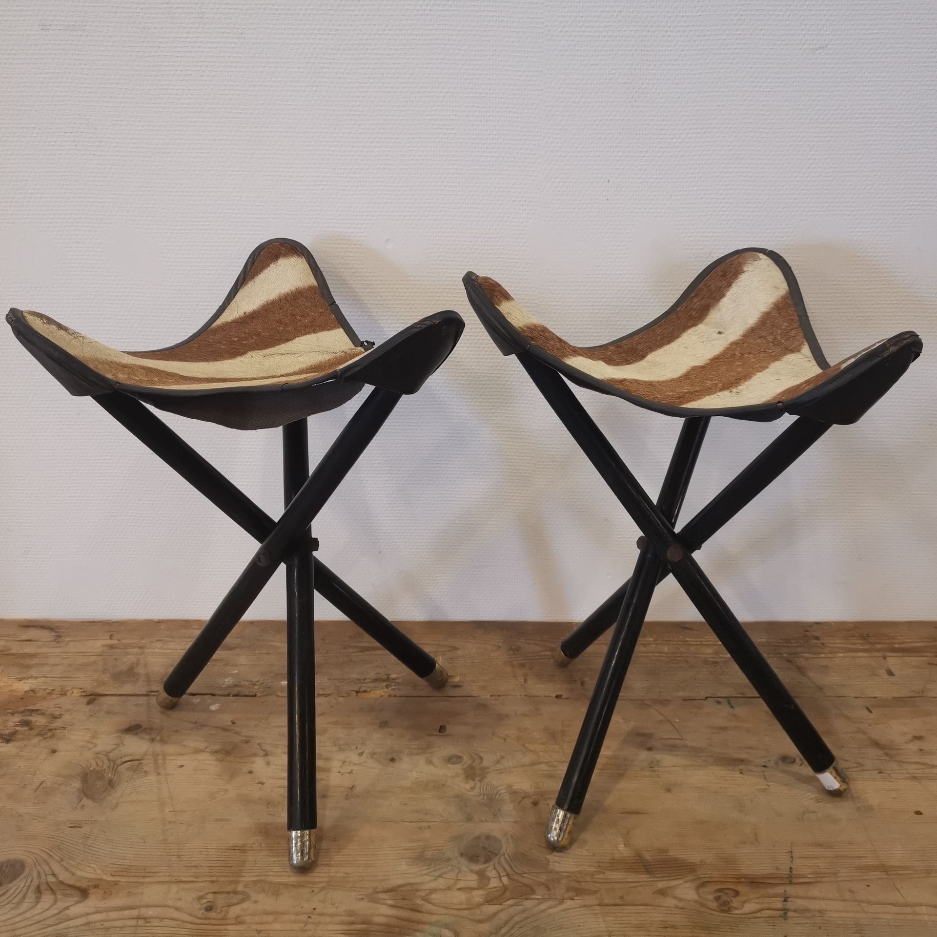 Null 60年代的作品。一对三脚架折叠凳，发黑的木腿，斑马皮装饰。高度：53厘米。裂缝，缺失的部分。