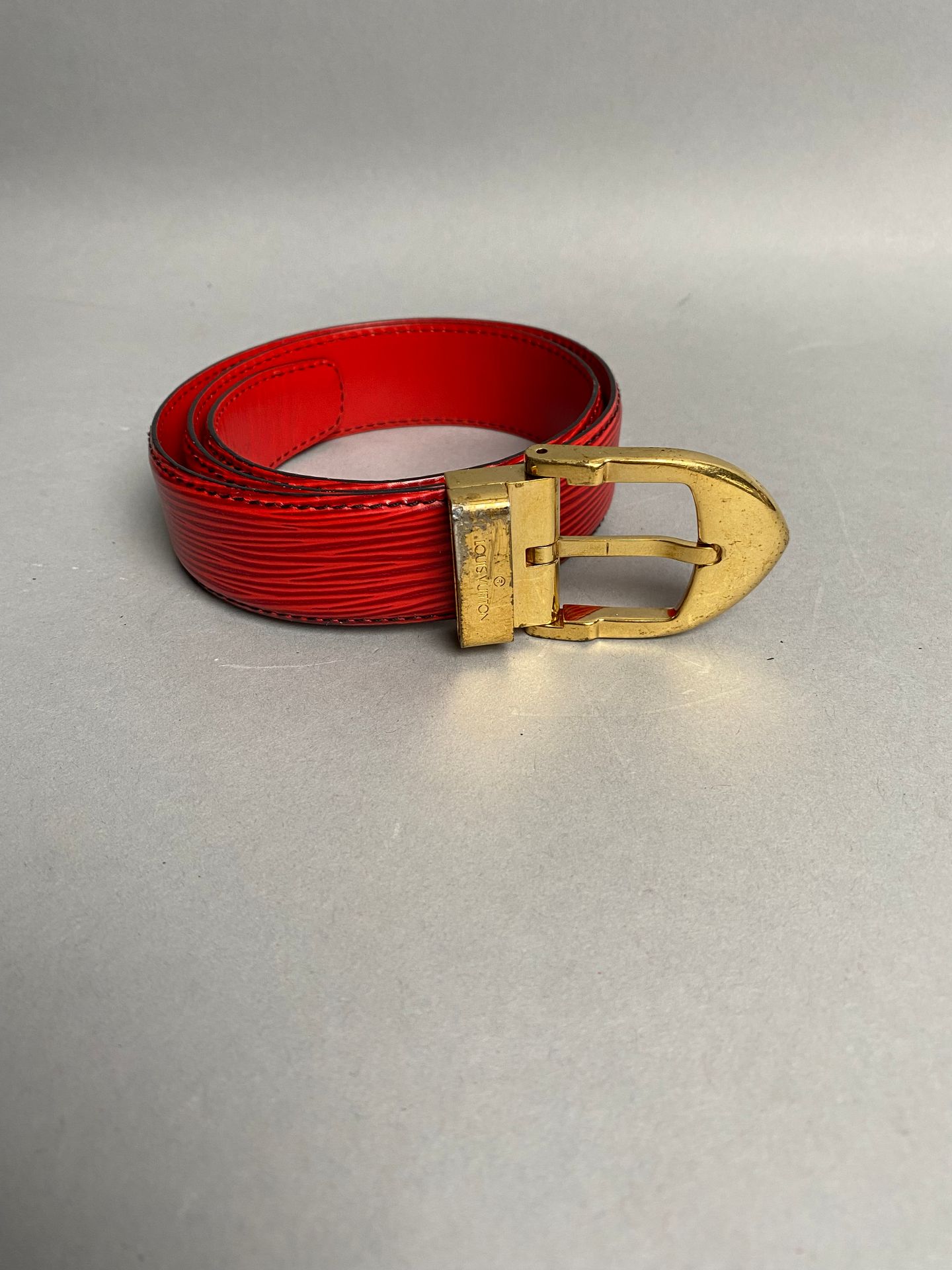 LOUIS VUITTON. Red leather belt, gold metal buckle. Size…