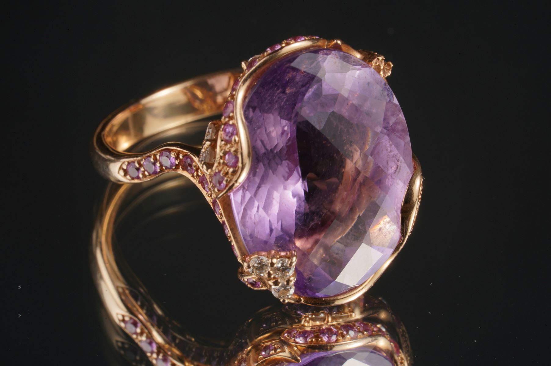 Null 玫瑰金戒指，中央镶嵌着一颗切割好的紫水晶，镶嵌着粉红色的宝石和亮片。 重量为9.3克。一边的石头不见了。编号59/60。
