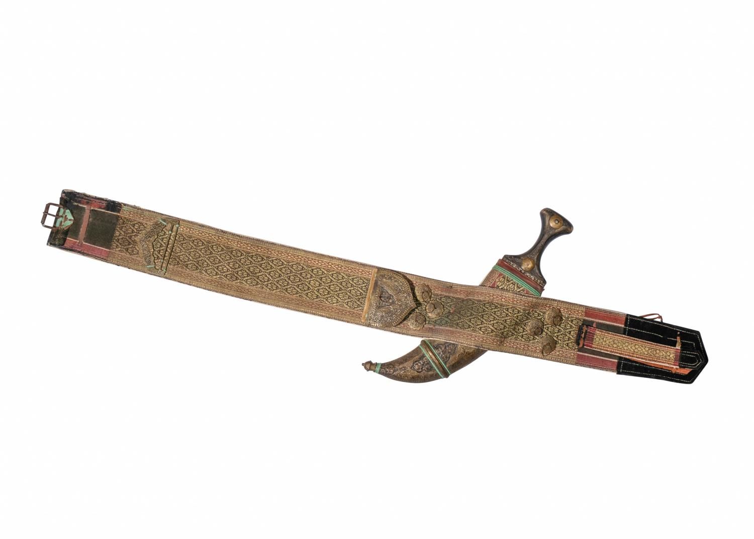 Null 中东匕首JAMBIYA与刀鞘和腰带。19世纪/20世纪
 
 匕首弯曲，带有双刃刀，刀柄用黄铜装饰，浮雕有叶子和叶子的卷轴，厚厚的手工刺绣腰带有复杂的&hellip;