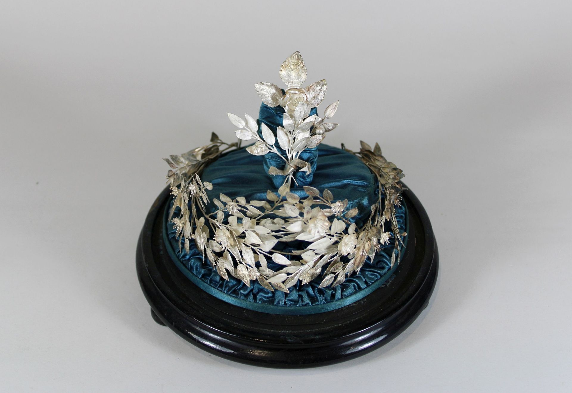 Silberkranz unter Glas 玻璃下的银质花环，月桂花环，金属，镀银，铺在绸缎上，装饰品，20世纪，高约21厘米，长约20厘米，状态因年代而异。