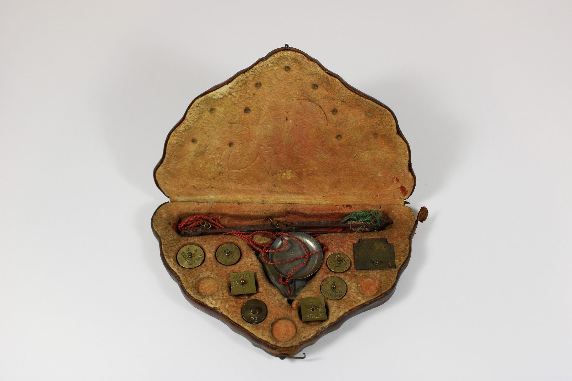 Münzwaage 硬币秤，有5个圆形和2个方形的黄铜砝码，黄铜制成的秤和秤盘，装在一个有皮革衬里的箱子里，上面有棕色的压花皮革。尺寸：18 x 11 x 3厘&hellip;