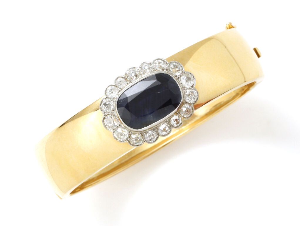 Null 镂空黄金（750）手镯，在明亮式切割钻石的衬托下，镶嵌着一颗椭圆形切割蓝宝石。
棘轮扣和八个安全别针。
毛重：55.6克。- 宽度：6.5厘米。
所有&hellip;