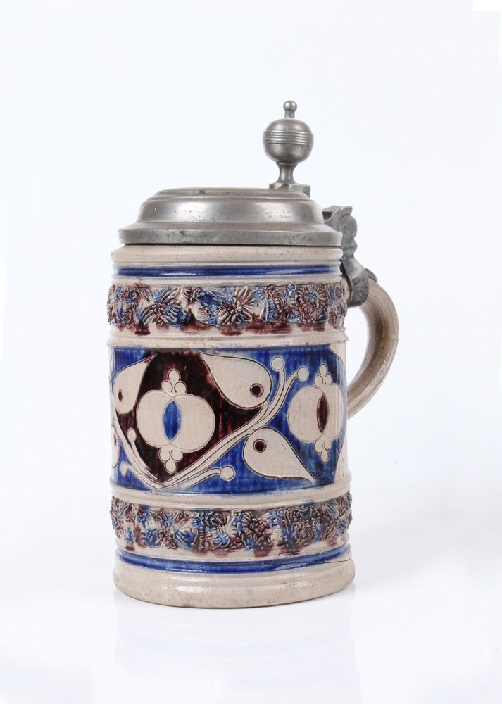 Null 滚轮壶。威斯特瓦尔德，18 世纪 石器，灰身，盐釉，钴蓝色和锰彩绘。壶壁饰有风格化的花朵，边饰为印花带。刻有 "4 "字样。锡座。高：21.5 厘米。&hellip;