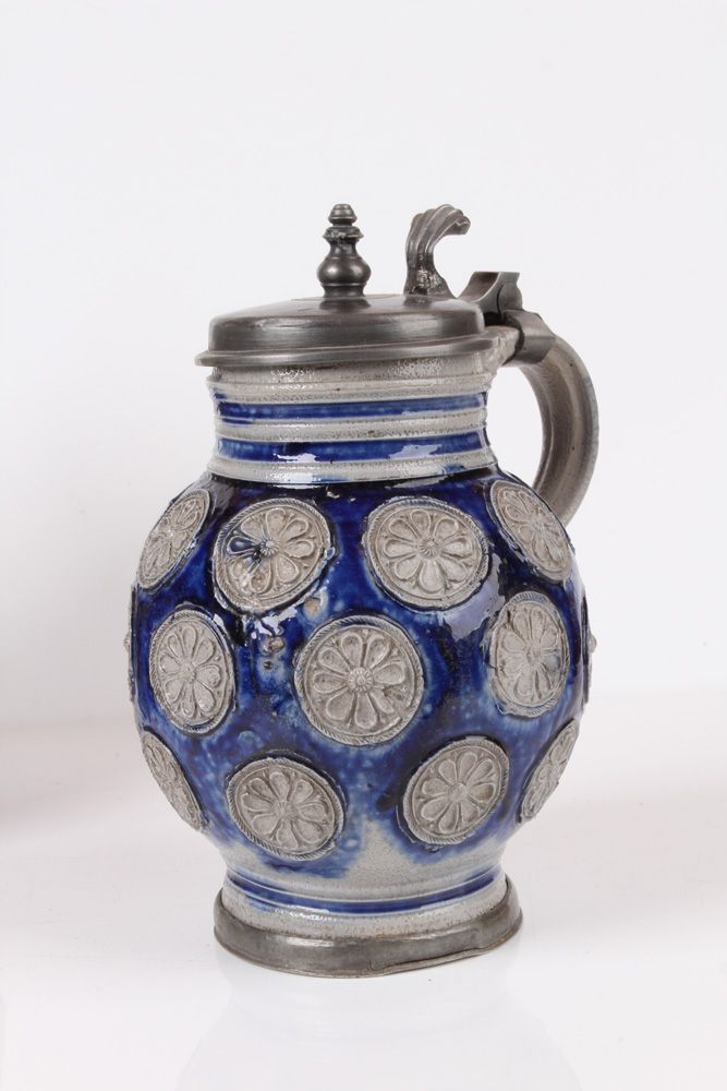 Null 球形壶。威斯特瓦尔德，约 1700 年，石器，灰色壶身，盐釉和钴蓝色彩绘。壶身四周装饰有玫瑰花纹印章。凹槽卷柄，锡制底座。高：20 厘米。