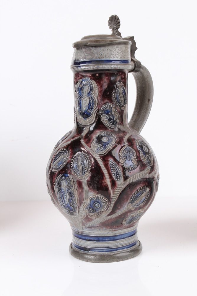 Null 窄颈壶。维斯特瓦尔德，约 1700 年，石器。灰色盐釉壶身，有钴蓝色和锰彩绘。刻有各种花朵的装饰。花朵。带凹槽的卷柄。锡座。高：25.5 厘米。唇缘水&hellip;