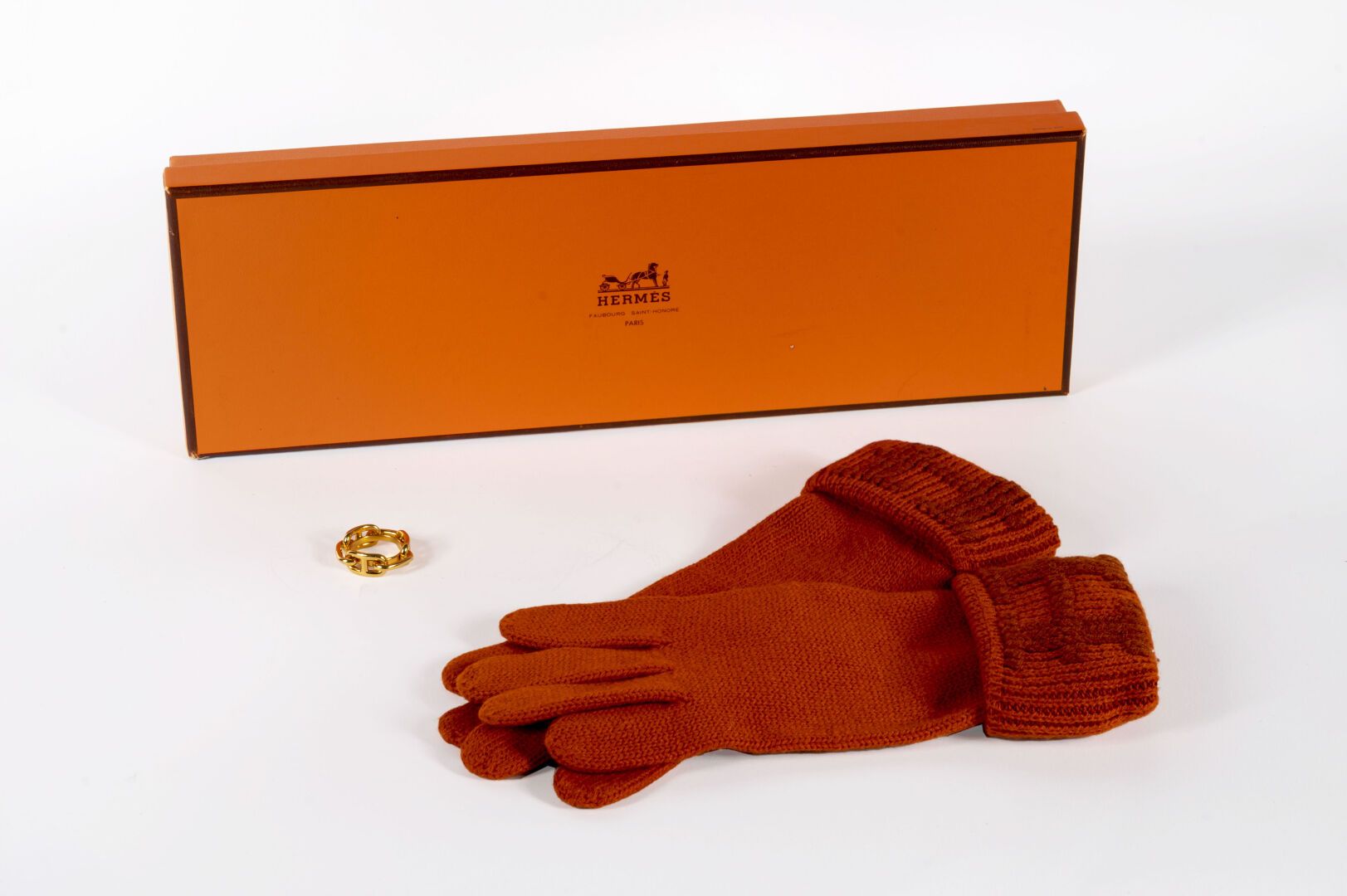 HERMES 地段包括。

- 橙色羊绒手套一对，尺寸中等

- 金色金属围巾戒指，墨链图案

箱子