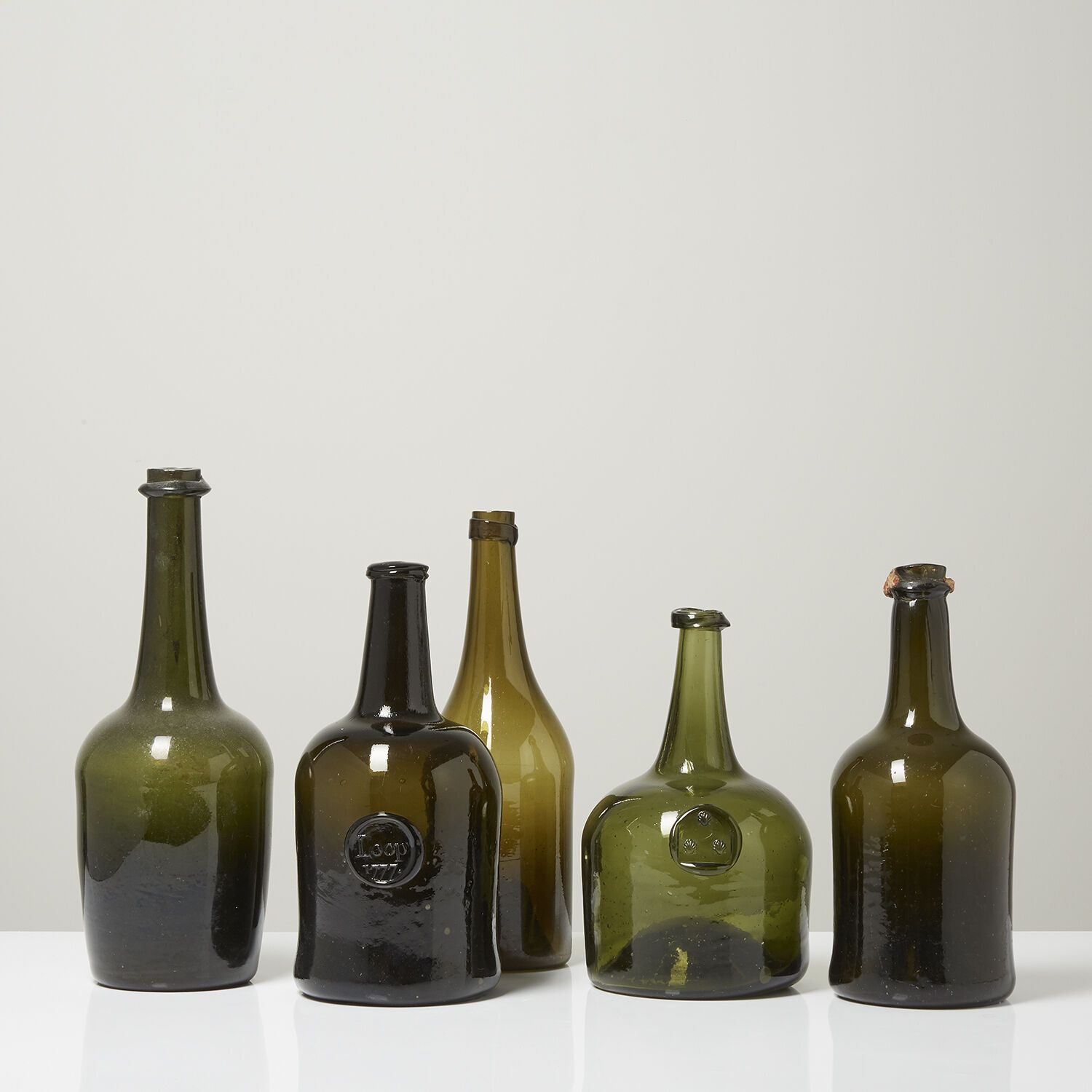 LOT DE CINQ BOUTEILLES EN VERRE TEINTÉ VERT, ÉPOQUE XVIIIe SIÈCLE 一套五个绿色的有色玻璃瓶。
&hellip;