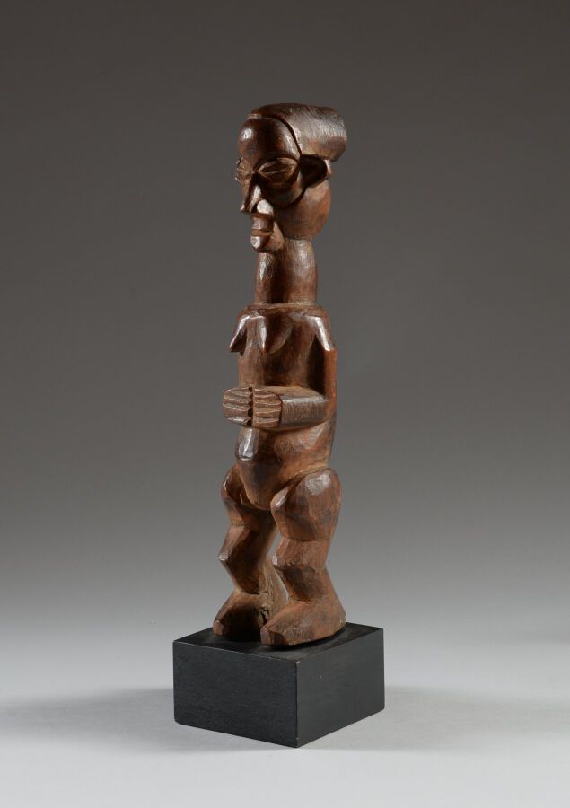 Null SUKU，刚果民主共和国。

硬木，棕色铜锈。

保护性雕像，代表一个女性的脚，挖空的手在躯干上相遇，强大的颈部被一张有表情的脸和高浮雕的耳朵顶着。
&hellip;