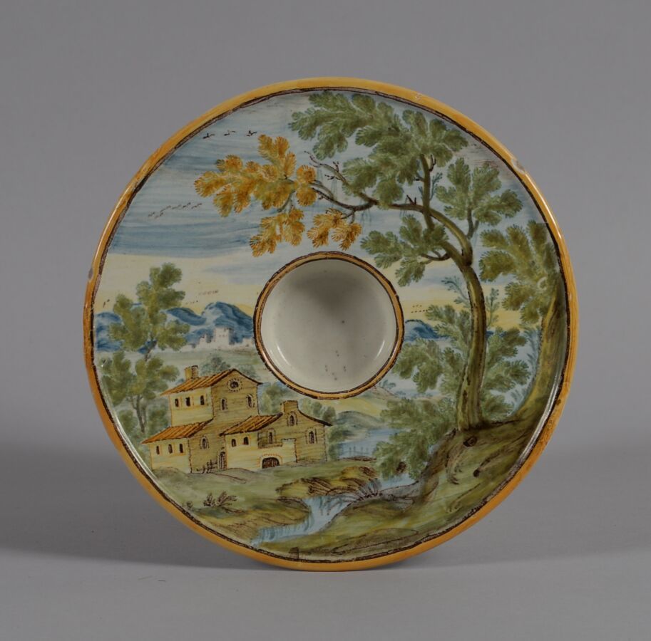 Null 意大利-卡斯泰利
多色陶器的圆形盘子，中央保留有建筑和树木的景观。
18世纪
直径17厘米
BE