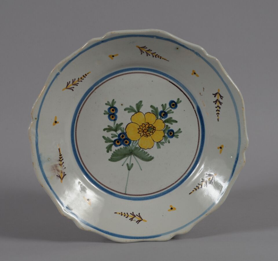 Null ǞǞǞ
一个多色陶盘，装饰着一朵大的黄花，周围是小的蓝花。
19世纪
直径23厘米
边缘有小缺口