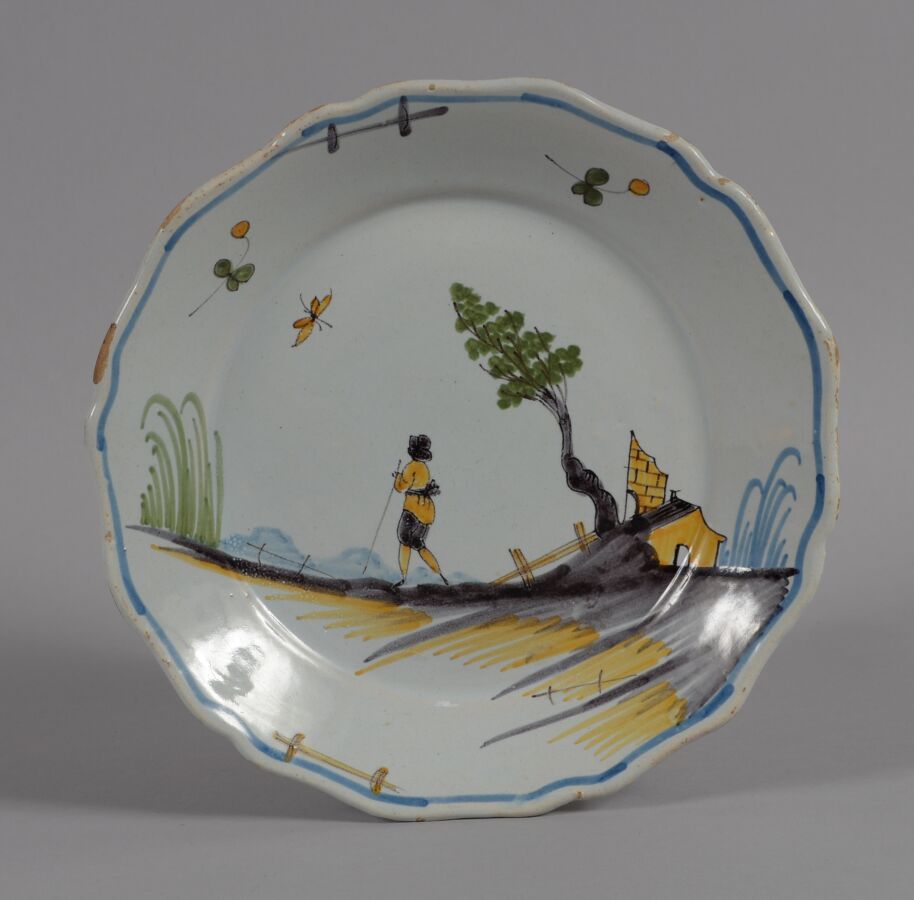 Null 罗歇勒（LA ROCHELLE
一个多色陶盘，上面装饰着一个走在有树和房子装饰的土丘上的人物。
18世纪
直径23厘米
边缘有轻微缺釉的BE