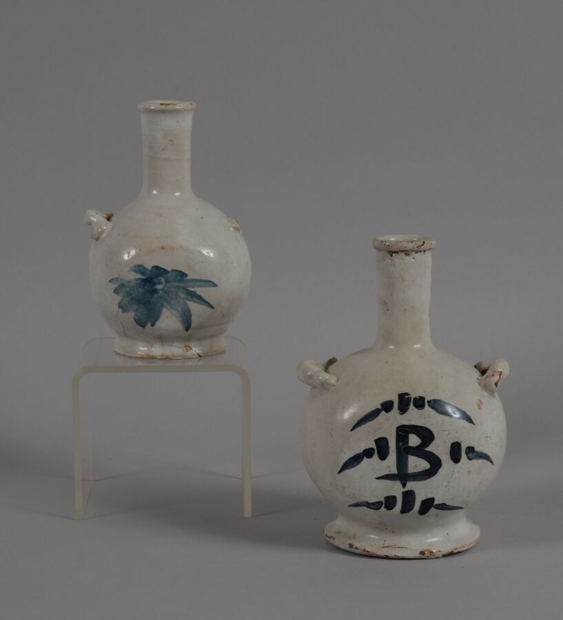 Null ǞǞǞ
两件陶制的瓶子，有两个圈，蓝色的单色装饰。
18世纪
高度为14.5和17厘米
一个是破损缺失的环，另一个是脖子上的头发